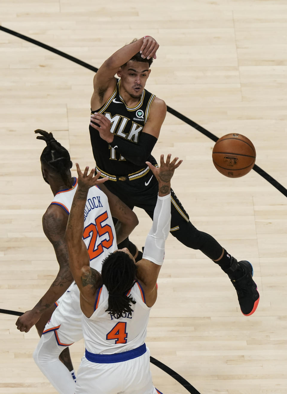 Atlanta Hawks' Trae Young (11) passes the ball against New York Knicks' Derrick Rose (4) and Reggie Bullock (25) during the first half in Game 4 of an NBA basketball first-round playoff series Sunday, May 30, 2021, in Atlanta. (AP Photo/Brynn Anderson)