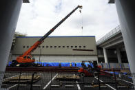 Construction workers lift a steel beam into position at Tokyo Metropolitan Gymnasium, one of venues for the postponed Tokyo 2020 Olympics Tuesday, April 6, 2021, in Tokyo. Many preparations are still up in the air as organizers try to figure out how to hold the postponed games in the middle of a pandemic. (AP Photo/Eugene Hoshiko)