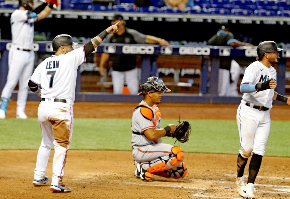 Miami Marlins Sandy Leon (7) and Miguel Rojas (19) score in the fifth inning as Baltimore Orioles catcher Pedro Severino (28) watches at loanDepotpark in Miami, Florida, Wednesday, April 21, 2021.