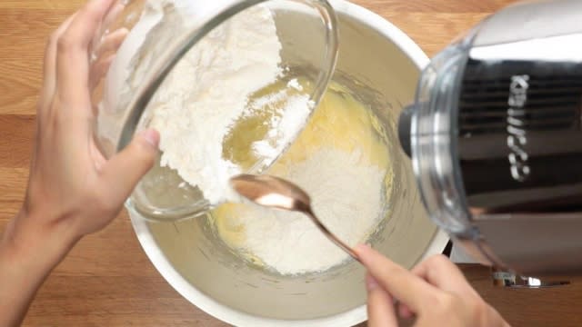 Adding flour to cake batter in mixing bowl