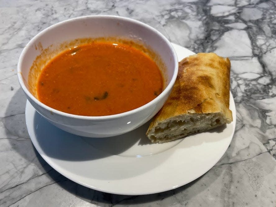 bowl of trader joe's tomato feta soup with a piece of bread next to it