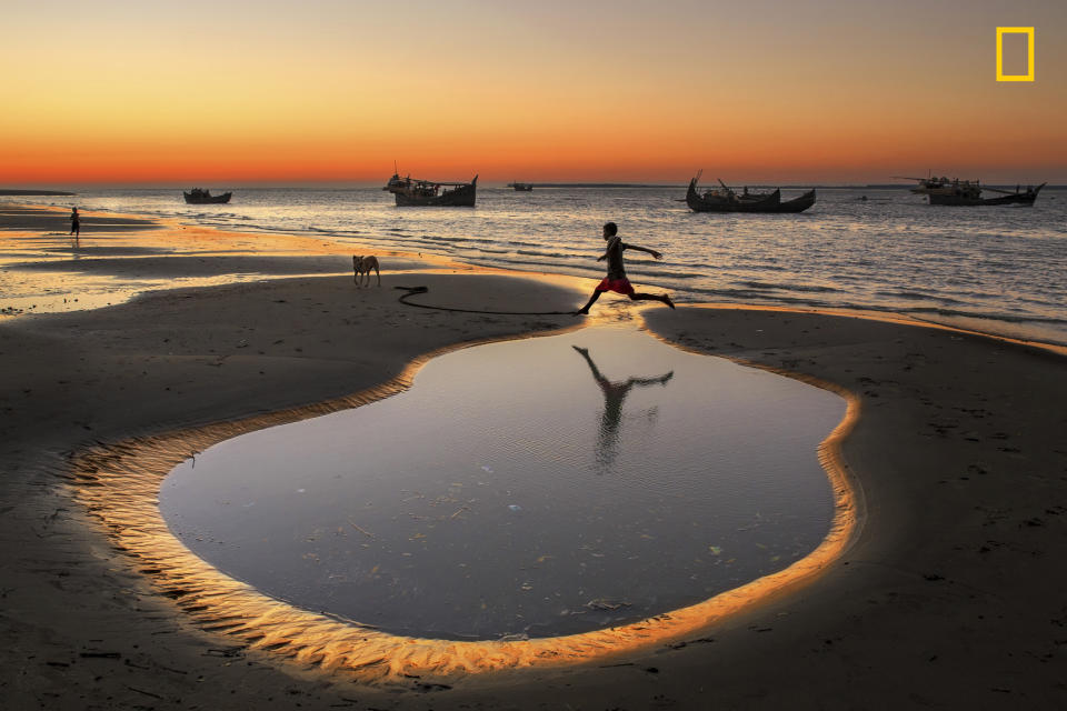 <p>A boy crossing a little pond beside a sea beach in a village in a Cox’s Bazar, Bangladesh. In the village more than 5000 families are engaged with dry fish processing. Their children have no modern toys to play, so some times they play and make fun by themselves like jumping or running. (Photo: Yousuf Tushar/National Geographic Travel Photographer of the Year Contest) </p>