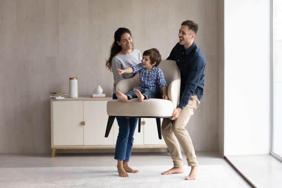 Parents carrying young child on chair at home - properties in trust