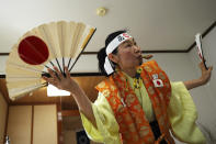 Olympic fan Kyoko Ishikawa shows her cheering at her home Saturday, April 10, 2021, in Tokyo. Ishikawa, president of an IT company, has attended every Summer Olympics since Barcelona in 1992, becoming famous as an unofficial "International Olympic Cheerleader." She relishes joining in with fans from everywhere to cheer for their athletes. Her headband reads: "Win." (AP Photo/Eugene Hoshiko)