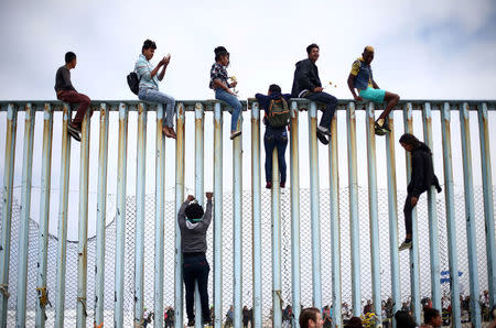Members of a caravan of migrants from Central America climb up the border fence between Mexico and the U.S., as a part of a demonstration prior to preparations for an asylum request in the U.S., in Tijuana, Mexico. REUTERS/Edgard Garrido