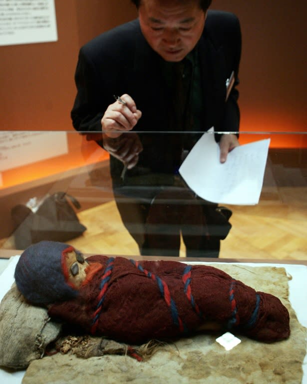 A journalist looks at a baby mummy which was unearthed at an ancient tomb in Chinese city of Qarqan. The Kyrgyzstan mummy "has tremendous value in filling in the gap" as a case study between Xinjiang's Tarim Basin and Western Eurasia, experts say