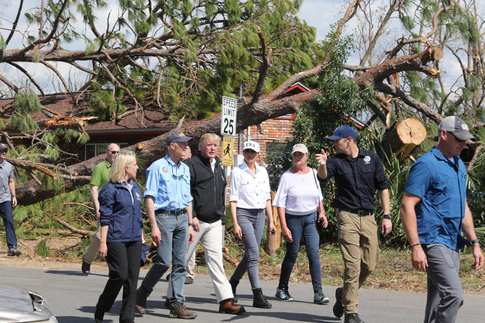 Florida Gov. Rick Scott, second from left, President Donald J Trump, center left, Melania Trump, center right, and Lynn Haven, Fla., Mayor Margo Anderson walk through a neighborhood in the storm-ravaged city Monday Oct. 15, 2018. (Michael Snyder/Northwest Florida Daily News via AP)