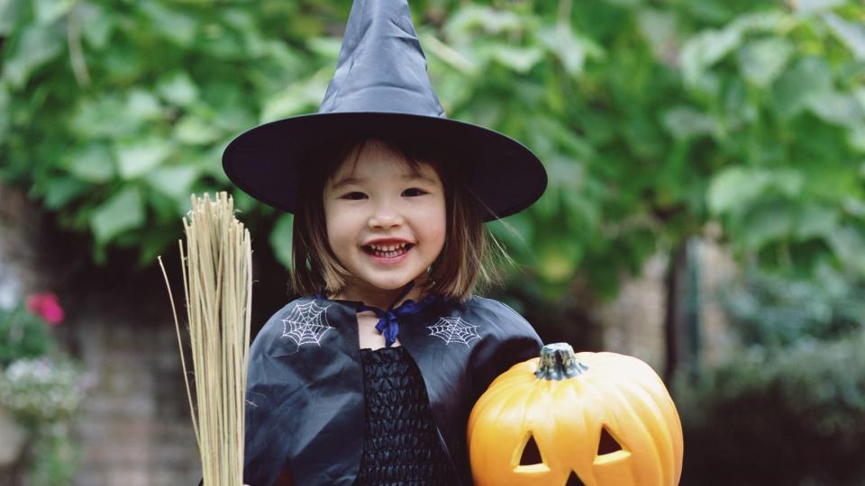 girl dressed as witch, holding pumpkin and broom, portrait