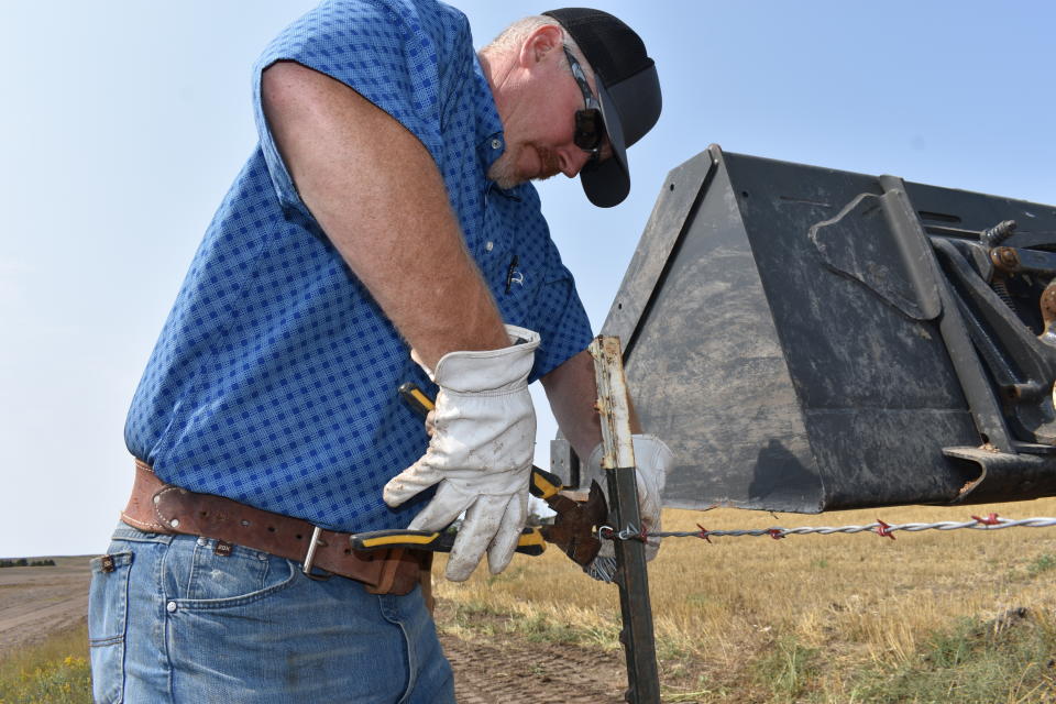 Howdy Lawlar repairs a barbed wire fence on his farm, Aug. 25, 2021, in McKenzie County, N.D. Lawlar says a rush of newcomers who more than doubled the county's population over the past decade have become part of McKenzie's "extended family." (AP Photo/Matthew Brown)