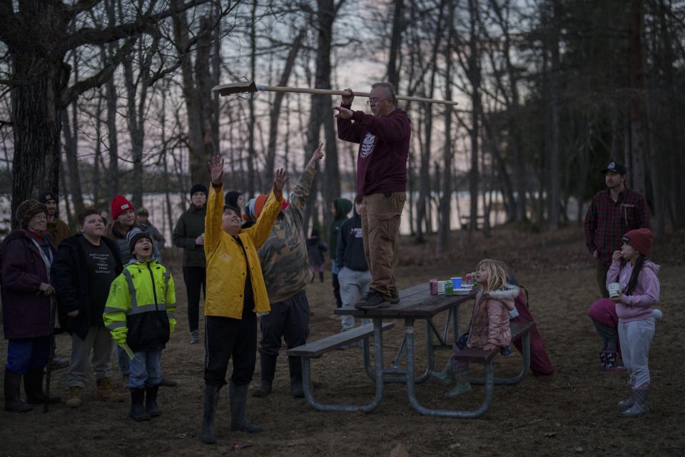 Mark Duffy, a member of the Red Cliff Band of Lake Superior Chippewa, stands on a picnic table while showing kids how to spearfish at a family and youth spearfishing event on Namekagon Lake, Friday, April 12, 2024, near Cable, Wis. (AP Photo/John Locher)