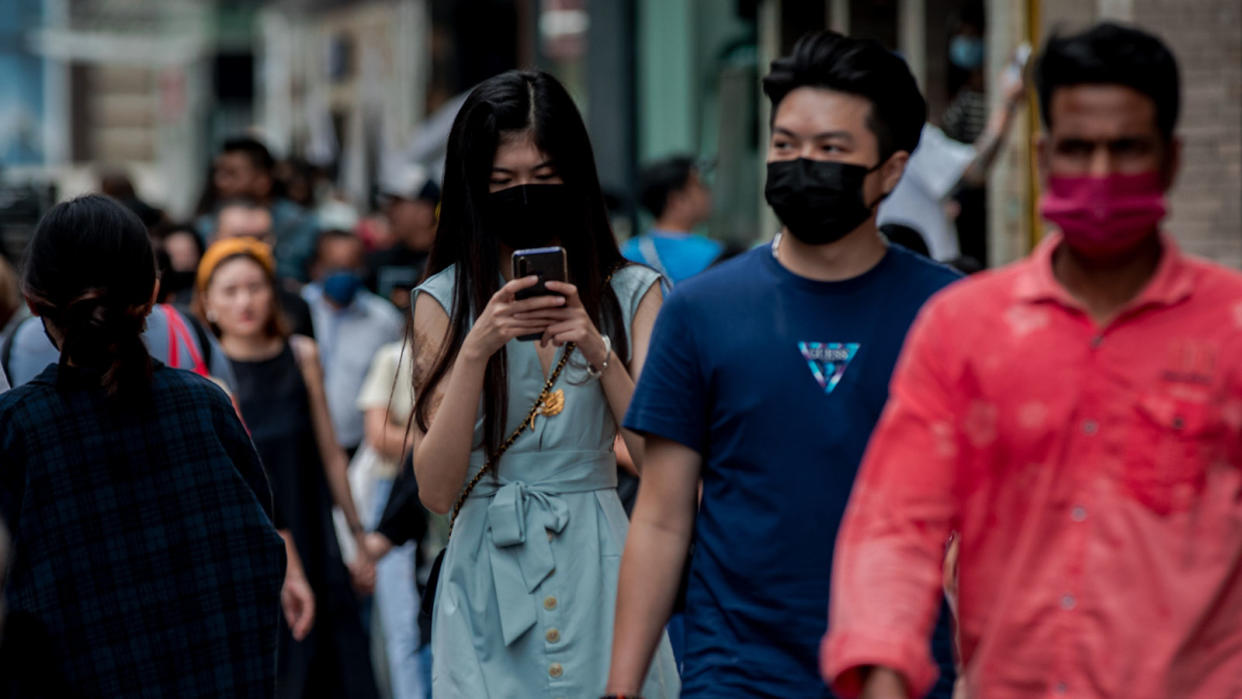 Young woman using her phone while walking on the street, illustrating youth voters participating in the General Election.