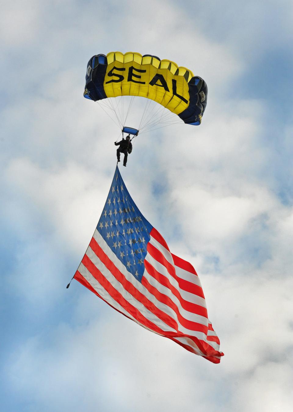 A member of the U.S. Navy Leap Frogs parachute team carries a U.S. flag onto Airline Stadium in Bossier City in 2015.