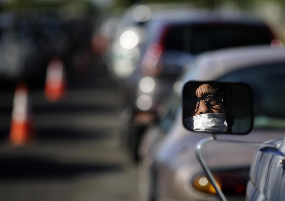 Guadalupe Guillen waits in line for food at a distribution center Thursday, July 23, 2020, in Brawley, Calif. Imperial County's poverty rate of 21% is among California's highest, putting more pressure on an area hard-hit by the coronavirus. (AP Photo/Gregory Bull)