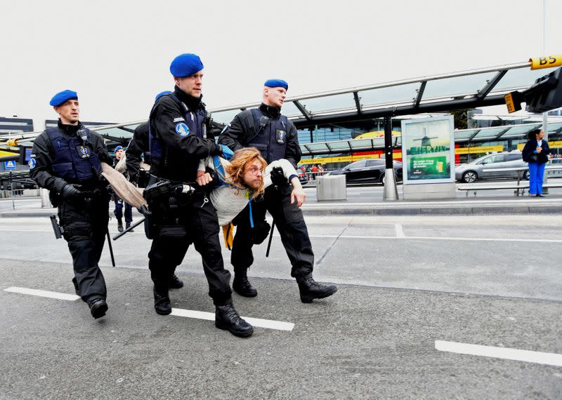 A protester is detained as Greenpeace stages a climate protest at Amsterdam Schiphol Airport in Schiphol