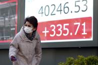 A person walks in front of an electronic stock board showing Japan's Nikkei 225 index at a securities firm Monday, March 4, 2024, in Tokyo. Japan's Nikkei 225 share benchmark has topped 40,000 for the first time as strong demand for technology shares keeps pushing the index higher.(AP Photo/Eugene Hoshiko)