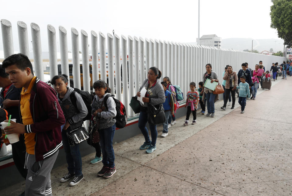 FILE - This July 26, 2018, file photo shows people lining up to cross into the United States to begin the process of applying for asylum near the San Ysidro port of entry in Tijuana, Mexico. A court-appointed committee has yet to find the parents of 628 children separated at the border early in the Trump administration. (AP Photo/Gregory Bull, File)