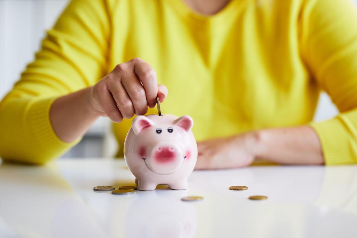 hands putting coins into piggy bank