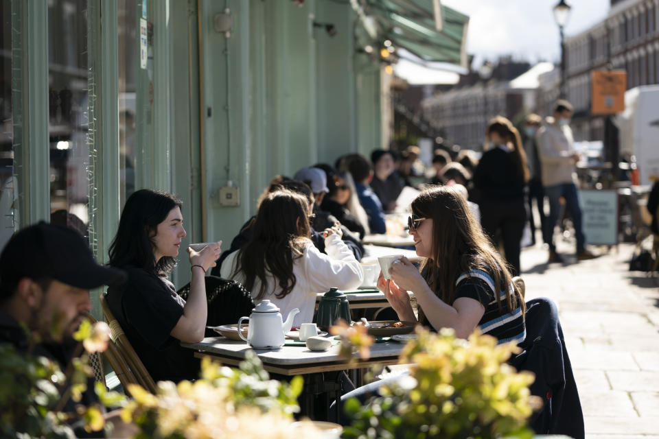 Customers sit outside a restaurant in Liverpool, Monday, April 12, 2021, as restaurants, bars and pubs can open and serve people who can be seated outside. Millions of people in England will get their first chance in months for haircuts, casual shopping and restaurant meals on Monday, as the government takes the next step on its coronavirus lockdown-lifting road map. (AP Photo Jon Super)