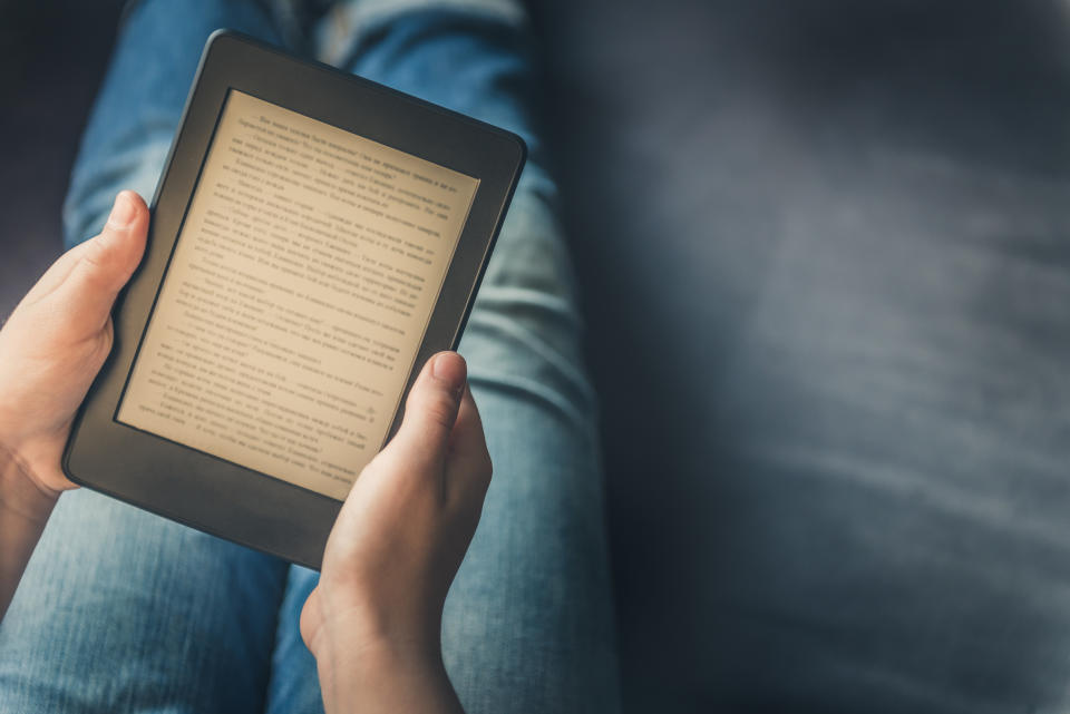 Girl is reading ebook on digital tablet device while relaxing on the sofa