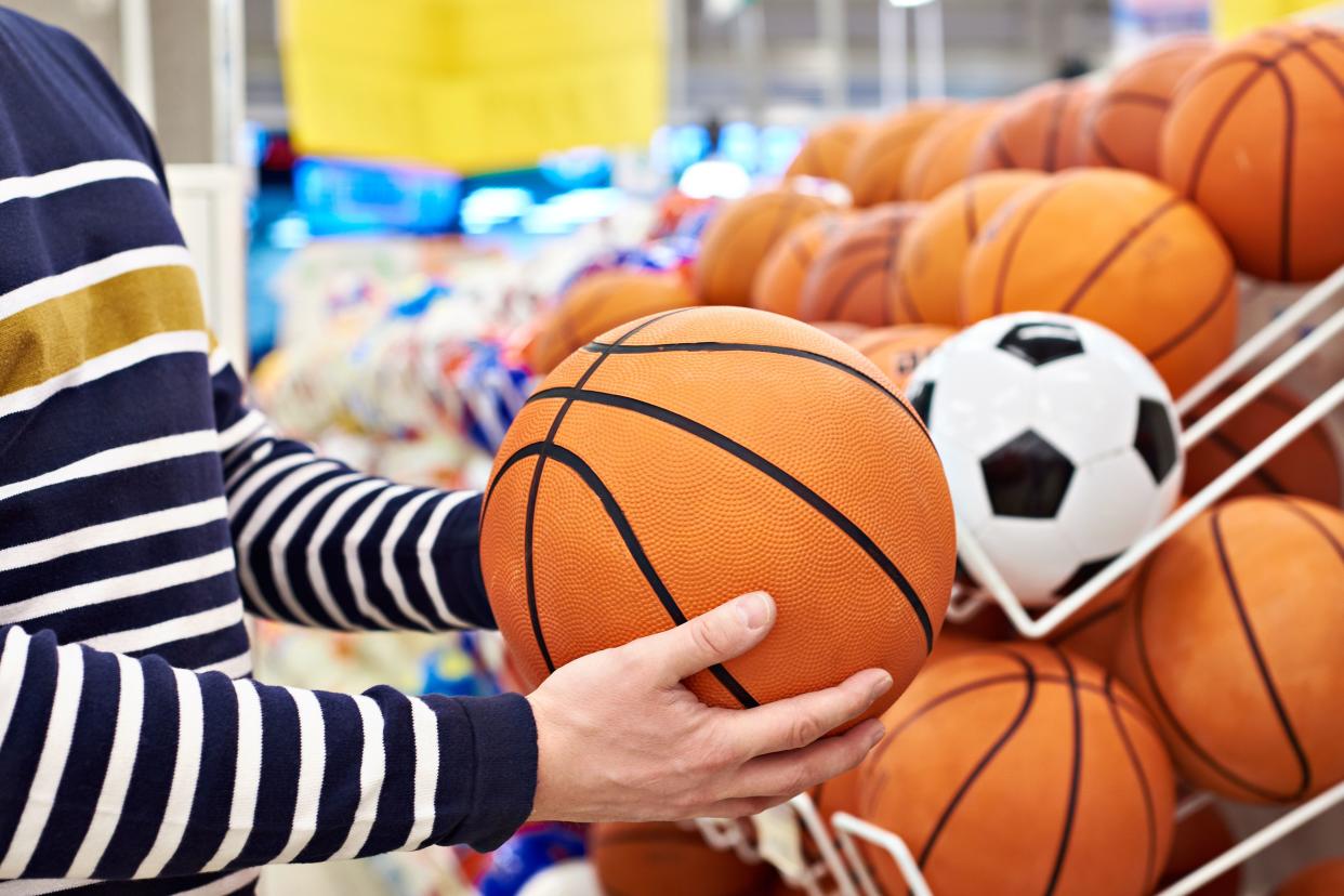 Buyer's hands with football and basketball in the sports shop