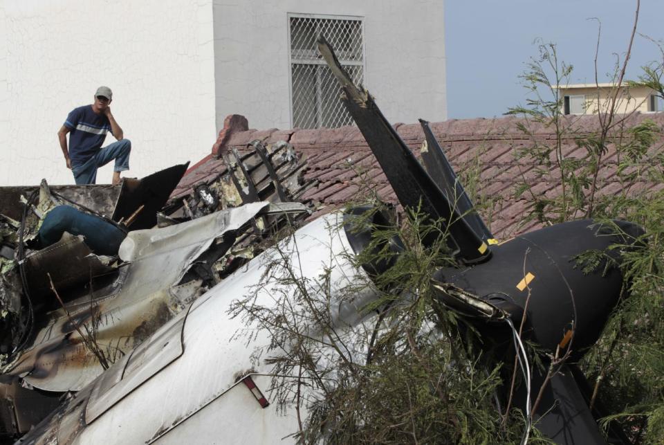 A local resident watches the forensic investigation among the wreckage of crashed TransAsia Airways flight GE222 on the outlying island of Penghu, Taiwan, Thursday, July 24, 2014. Stormy weather on the trailing edge of Typhoon Matmo was the likely cause of the plane crash that killed more than 40 people, the airline said Thursday. (AP Photo/Wally Santana)