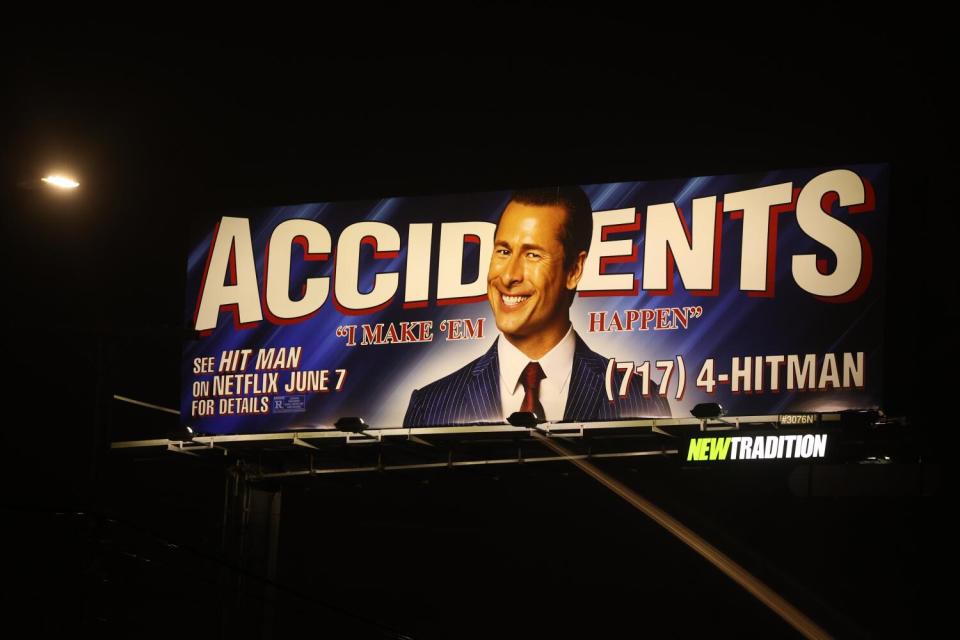 A billboard with a smiling man in front of the word “Accidents” is illuminated at night and advertises Netflix’s "Contract killer."