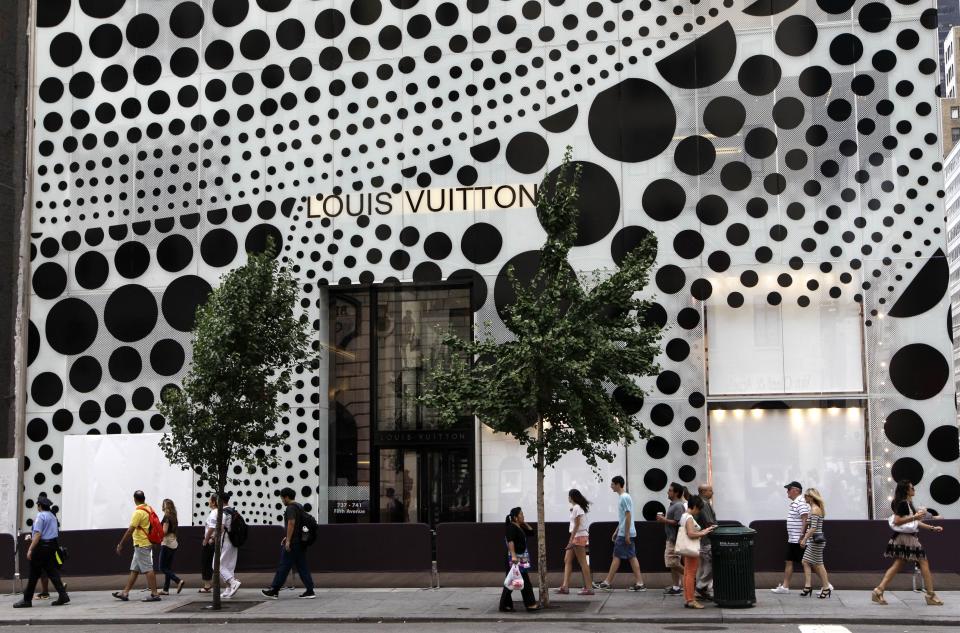 Pedestrians walk in front of Louis Vuitton's flagship Fifth Avneue store in New York, Tuesday, July 10, 2012, before the company unveiled windows and a collection collaboratively designed by Japanese artist Yayoi Kusama and Vuitton creative director Marc Jacobs. (AP Photo/Kathy Willens)
