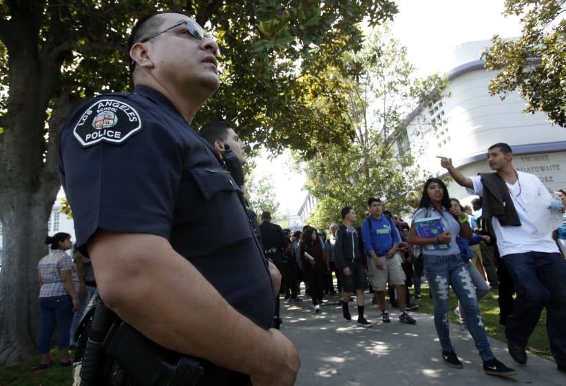 LAUSD police officer Jay Cueva watches as students get out of Manual Arts High School. The district has announced a new program in which school police will no longer issue citations to students for fighting, marijuana possession or other minor offenses.