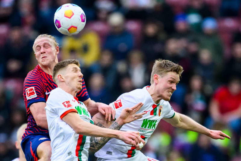 Leipzig's Xaver Schlager (L) and Augsburg's Kristijan Jakic (C) and Augsburg's Fredrik Jensen (R) battle for the ball during the German Bundesliga soccer match between FC Augsburg and RB Leipzig at WWK-Arena. Tom Weller/dpa