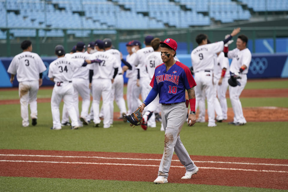 Dominican Republic's Jeison Guzman leaves the field as Japan players celebrate the team's 4-3 win in a baseball game at the 2020 Summer Olympics, Wednesday, July 28, 2021, in Fukushima, Japan. (AP Photo/Jae C. Hong)