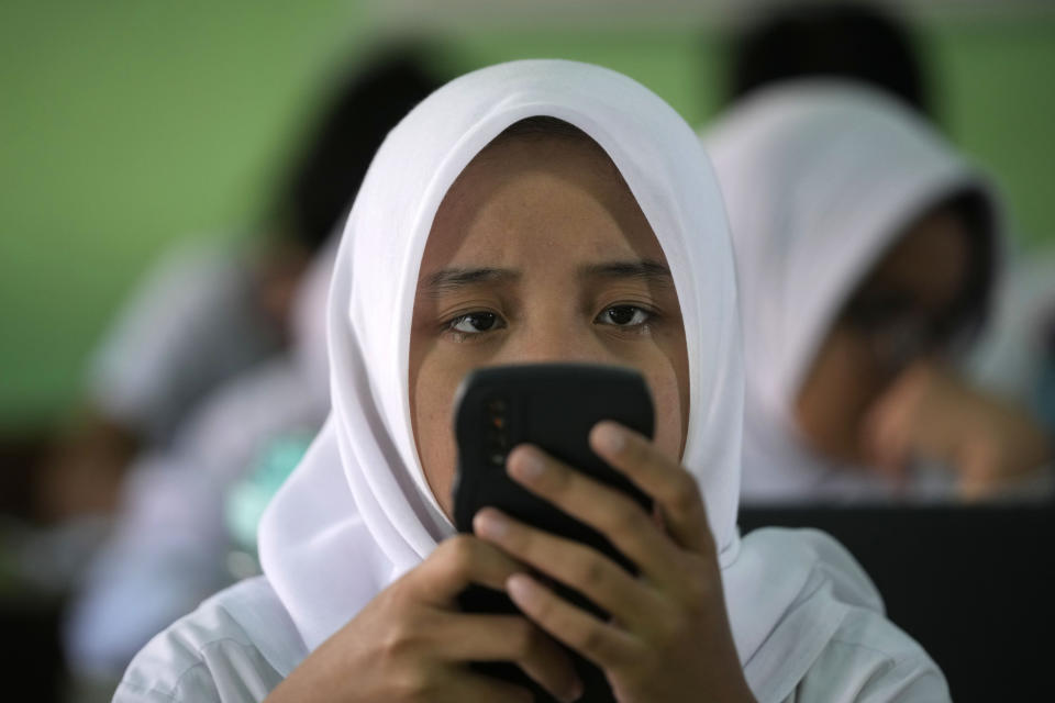 A student uses her mobile phone to work on an online exercise at SMAN 37 high school in Jakarta, Indonesia, Thursday, Jan. 25, 2024. As Indonesia votes this month to replace popular President Joko Widodo, all three candidates have all been aggressively seeking to win the votes of younger people, reaching out to them on the apps they use, through the K-pop music many love, and even video gaming events. (AP Photo/Dita Alangkara)