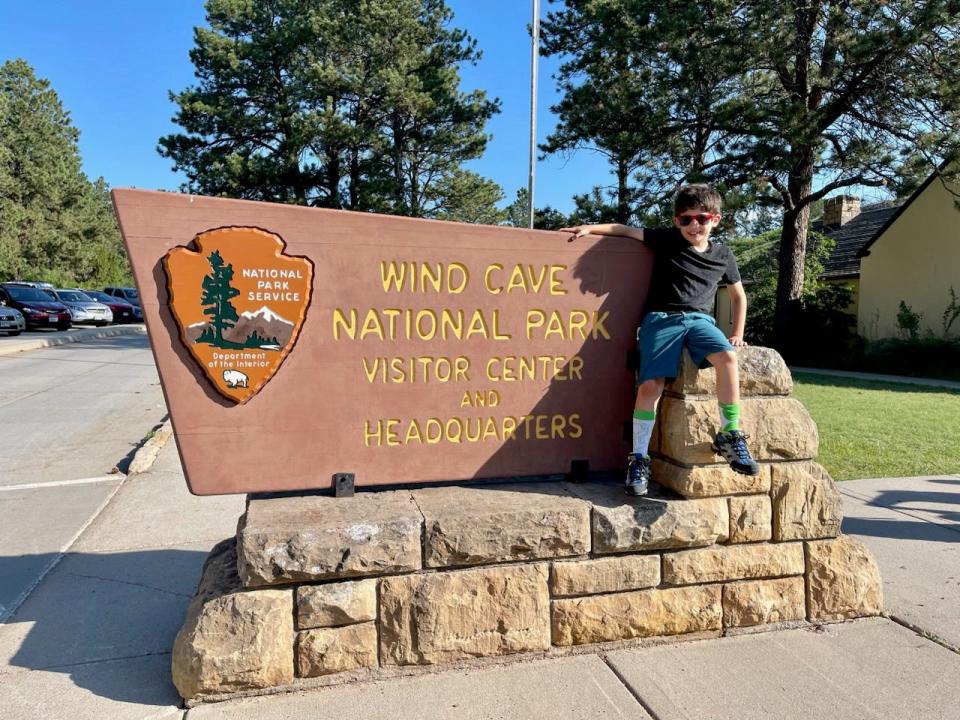 Boy posing with National Park Wind Cave sign 