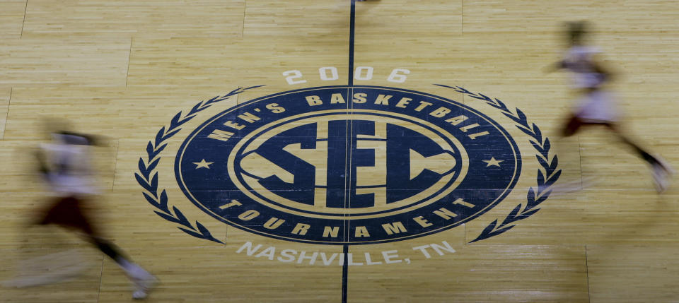 FILE - Arkansas players run past the Southeastern Conference logo during practice for the 2006 SEC men's basketball tournament March 8, 2006, in Nashville, Tenn. The NCAA and the nation's five biggest conferences have agreed to pay nearly $2.8 billion to settle a host of antitrust claims,a monumental decision that sets the stage for a groundbreaking revenue-sharing model that could start directing millions of dollars directly to athletes as soon as the 2025 fall semester. (AP Photo/Mark Humphrey, File)