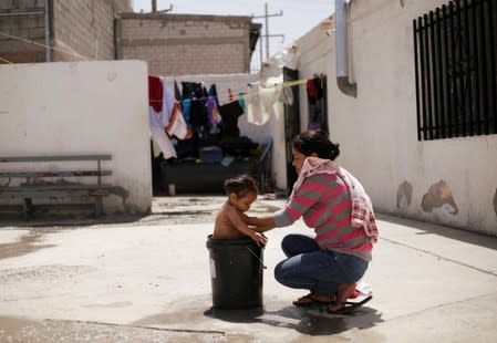 Guatemalan migrant Corio, who is waiting for her court hearing for asylum seekers that returned to Mexico to await their legal proceedings under a new policy established by the U.S. government, baths her daughter at migrant shelter in Ciudad Juarez