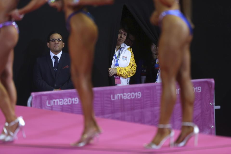 A volunteers watches the women's fitness final at the debut of bodybuilding as an official sport at the Pan American Games in Lima, Peru, Saturday, Aug.10, 2019. (AP Photo/Rodrigo Abd)