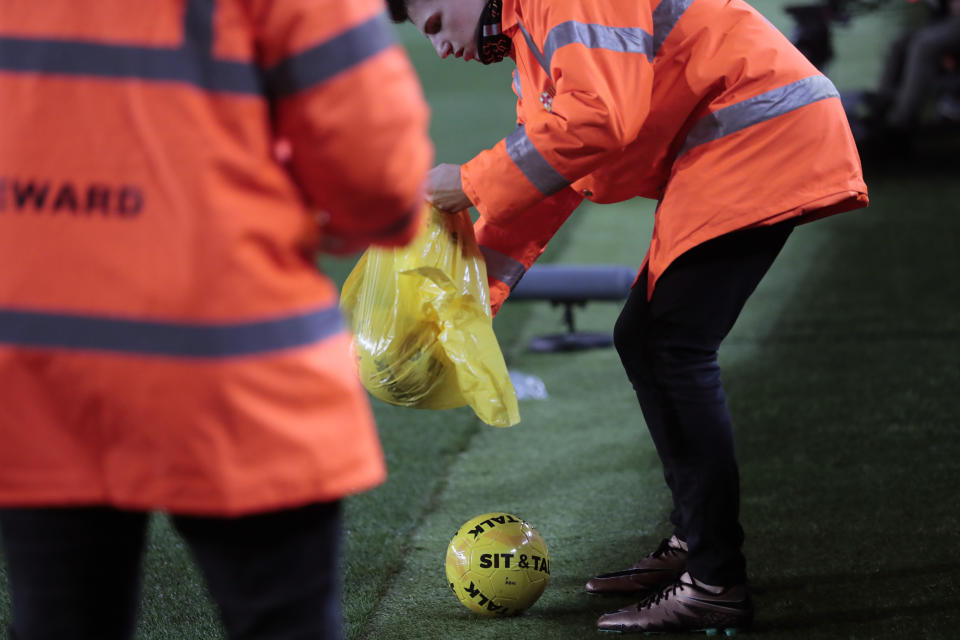 Stewards collect balls with the message "Sit & Talk" thrown on the pitch from the stands during a Spanish La Liga soccer match between Barcelona and Real Madrid at Camp Nou stadium in Barcelona, Spain, Wednesday, Dec. 18, 2019. Thousands of Catalan separatists are planning to protest around and inside Barcelona's Camp Nou Stadium during Wednesday's "Clasico". (AP Photo/Bernat Armangue)