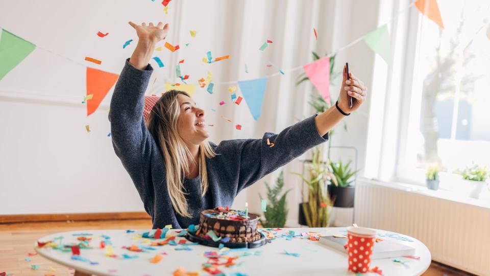 one woman, beautiful young woman using smart phone for selfie, she is celebrating her birthday alone at home