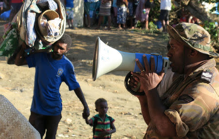 A member of the Vanuatu Mobile Force (VMF) gives instructions to residents carrying their possessions as they prepare to board a boat at Lolowai Port as they evacuate due to the Manaro Voui volcano continuing to emenate smoke and ash on Vanuatu's northern island of Ambae in the South Pacific, October 1, 2017. Picture taken October 1, 2017. REUTERS/Ben Bohane