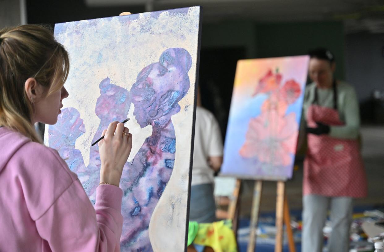 A woman paints during an art therapy workshop titled 