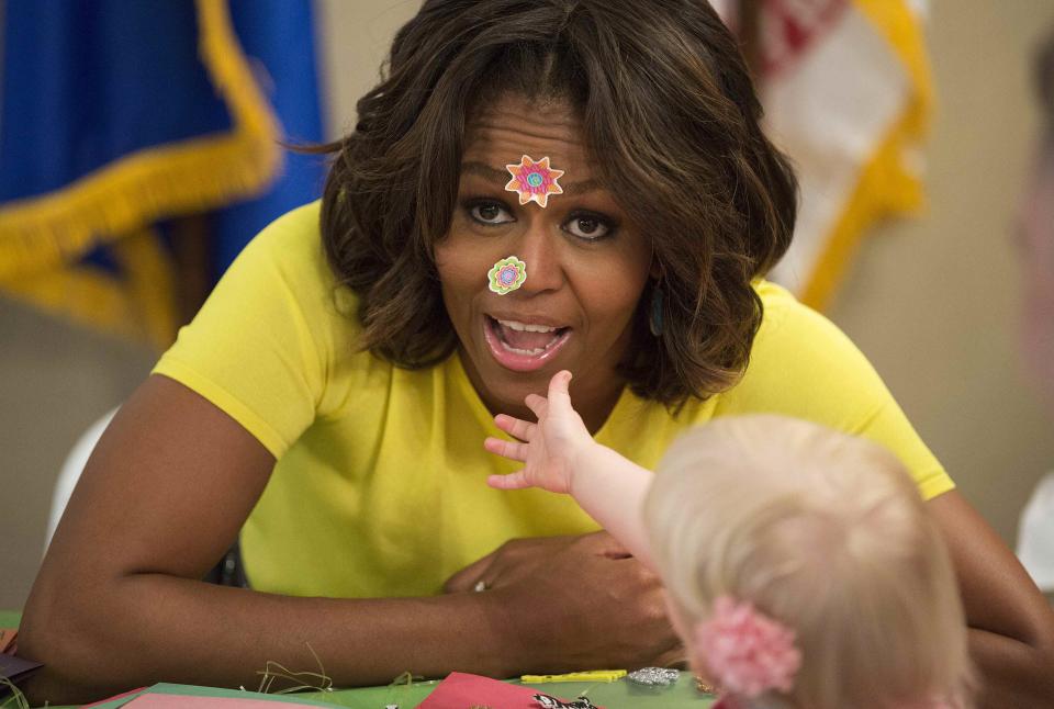 U.S. first lady Obama has stickers put on her face by 20-month-old Oppelt during visit with children at Fisher House at Walter Reed National Military Medical Center in Bethesda