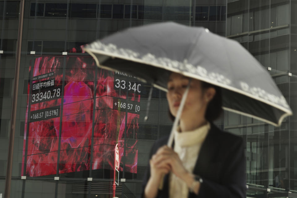 A woman walks by monitors showing Japan's Nikkei 225 index at a securities firm in Tokyo, Tuesday, Aug. 1, 2023. Asian shares mostly rose Tuesday, boosted by market optimism set off by a Wall Street rally despite lingering worries about inflation and regional growth. (AP Photo/Hiro Komae)