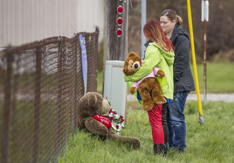 Alicia Greene and her daughter, Khloe Harris, 9, place signs and teddy bears at a small, makeshift memorial near the crash site in Rochester. Three kids from the same family were hit and killed by a pickup as they crossed Indiana 25 to board a school bus. A fourth child was hit and critically injured in the crash.