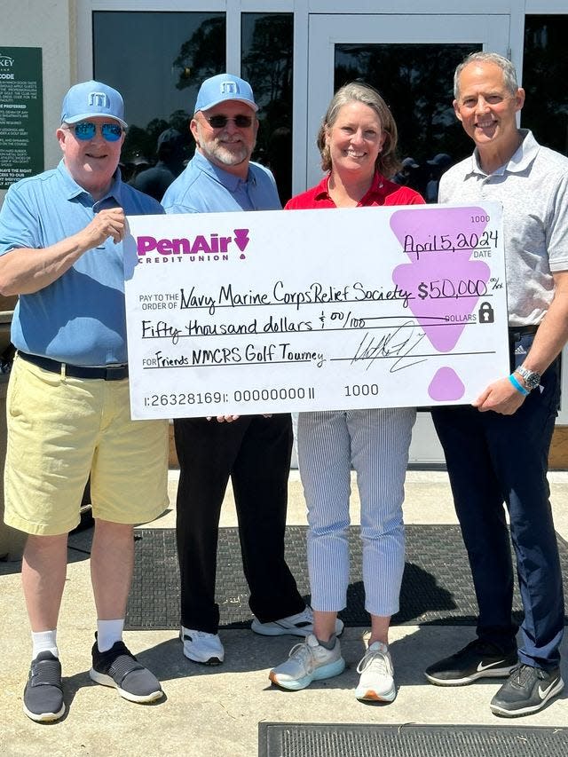 Navy-Marine Corps Relief Society Director Joy Barnes receives a $50,000 check from PenAir Board Chair Bob Jacobson, left, President/CEO Lee Morgan, middle, and retired Lt. Gen. Robert Ruark, right.