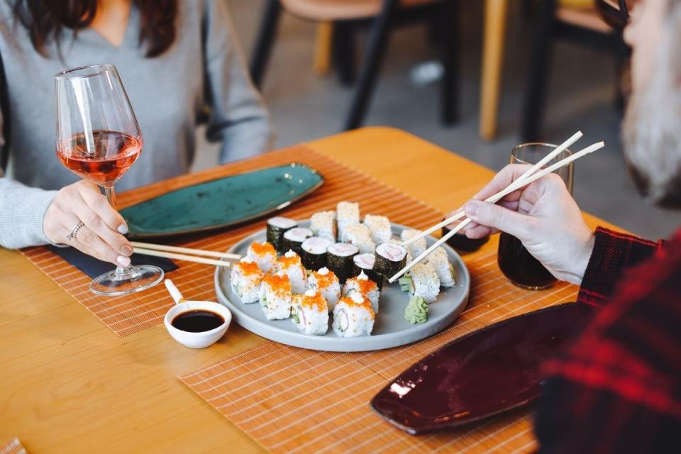 Couple shares plate of sushi with chopsticks
