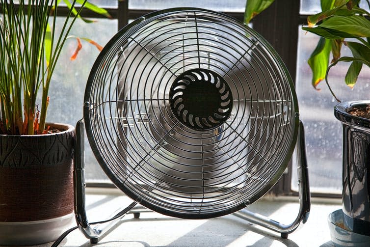 A spinning fan sits on a windowsill.