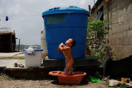 Luis Espinoza, 3, takes a bath next to a water tank, at his home in Charallave, Venezuela July 7, 2016. Luis's mother Oleydy Canizalez plans to have a sterilization surgery. REUTERS/Carlos Garcia Rawlins