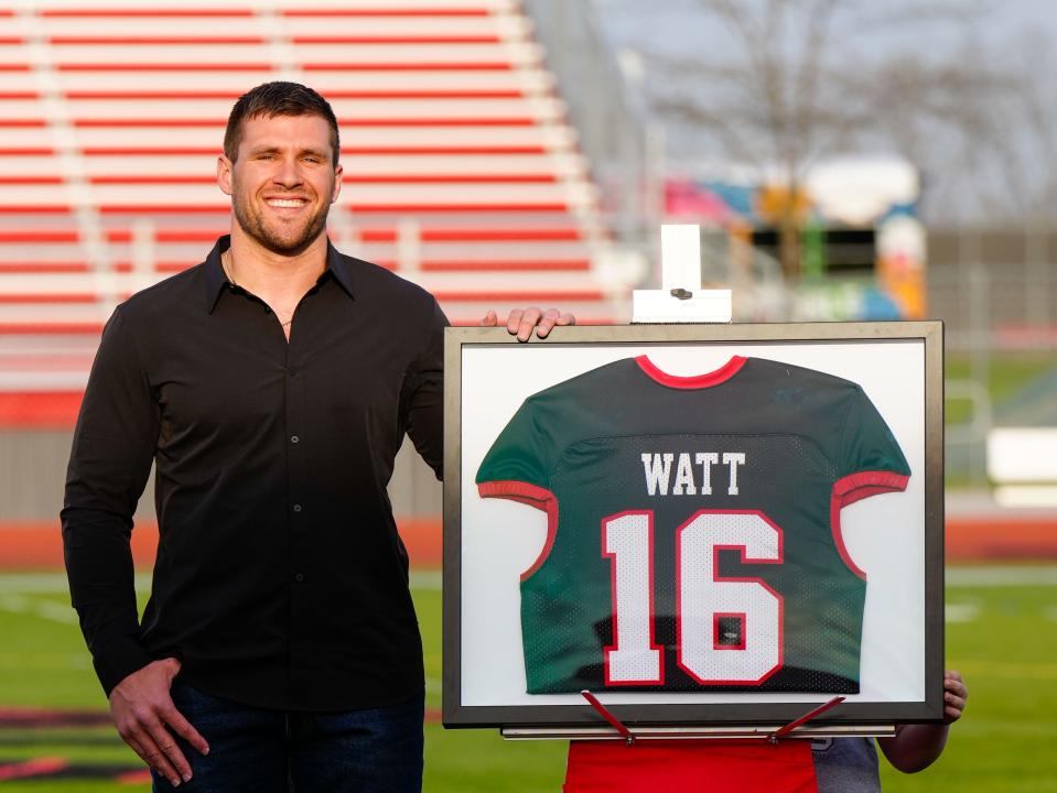 TJ Watt poses with his high school jersey during his and his brother Derek's jersey retirement ceremony at Pewaukee High School, Friday, May 5, 2023.