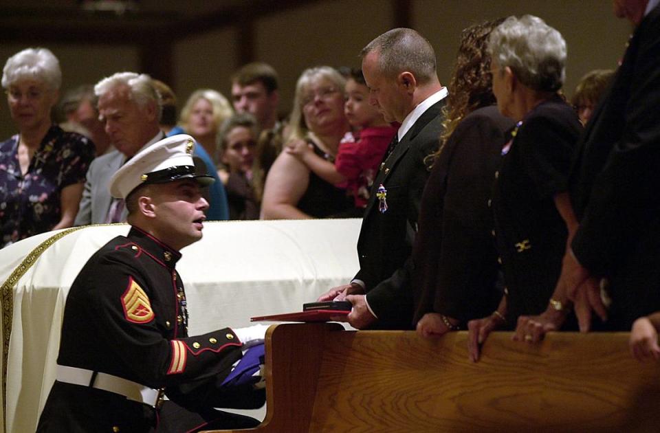 A marine offers Keith Dougherty, father of slain marine Lance Cpl. Scott Dougherty, the flag which was draped upon his casket during the young marine’s funeral at Our Lady Queen of Martyrs Church on July 17, 2004.