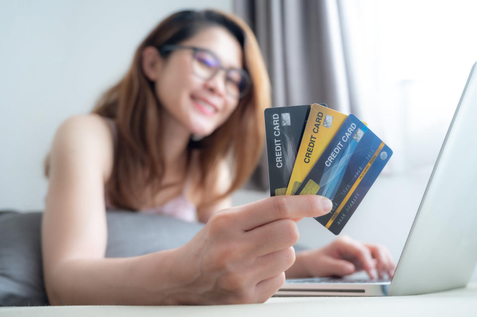 young woman holding three different credit cards