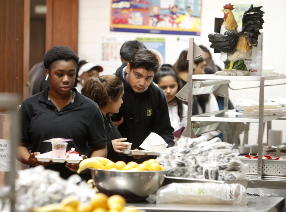 Students line up for lunch in the cafeteria at Lincoln High School in Dallas, Friday, March 13, 2020. During the coming extended spring break school closures, this cafeteria and others in the Dallas Independent School District will be providing lunches to students despite the closure of the school. (AP Photo/LM Otero)